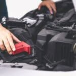 dettaglio di mani che controllano dentro il cofano di un'auto
