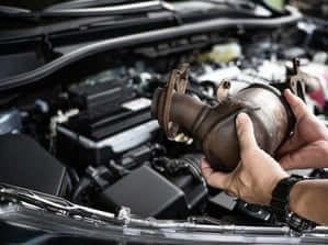 una mano tiene in mano un radiatore sul cofano aperto di un auto